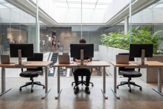 Free workspace area in a Bangkok mall with adjustable-height desks, external monitors, and natural daylight