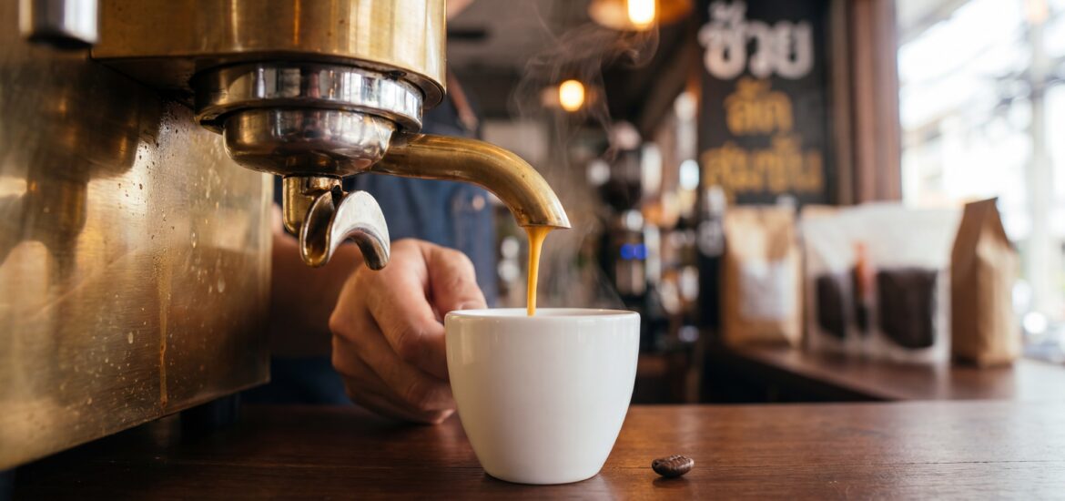 Espresso pour at a Bangkok specialty coffee bar with golden crema falling into a white ceramic cup and a brass machine